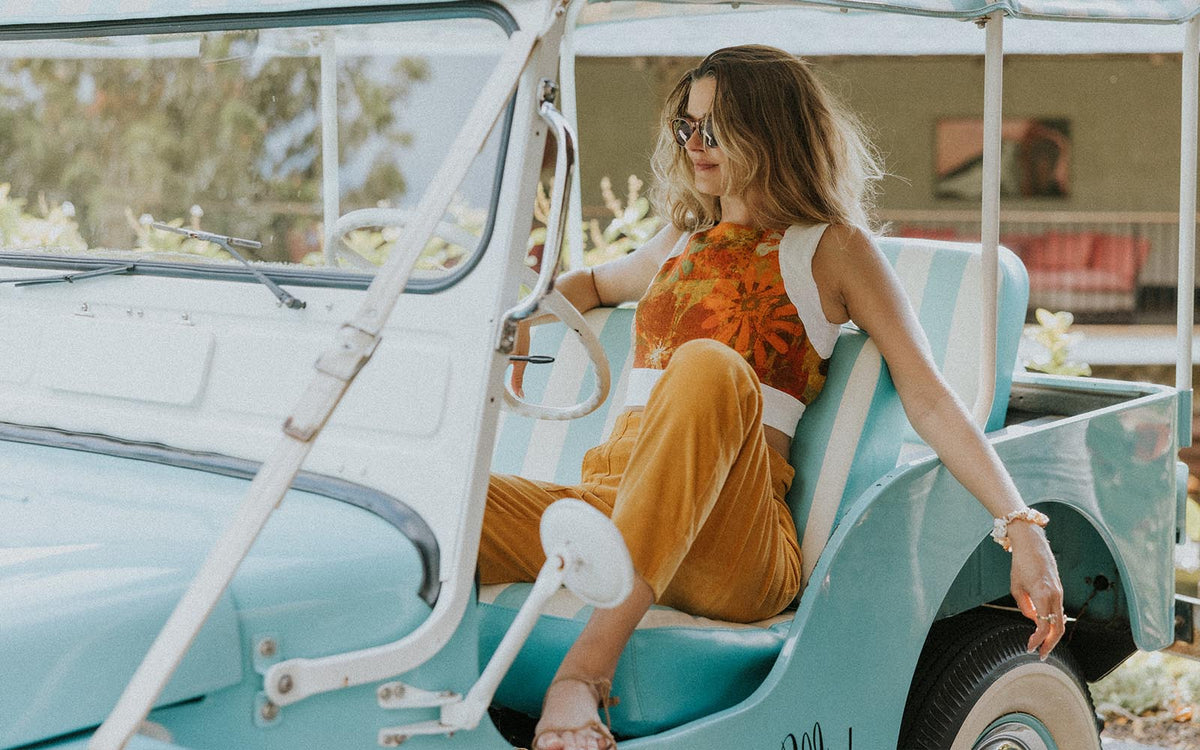 Model in an orange top in an open vintage car