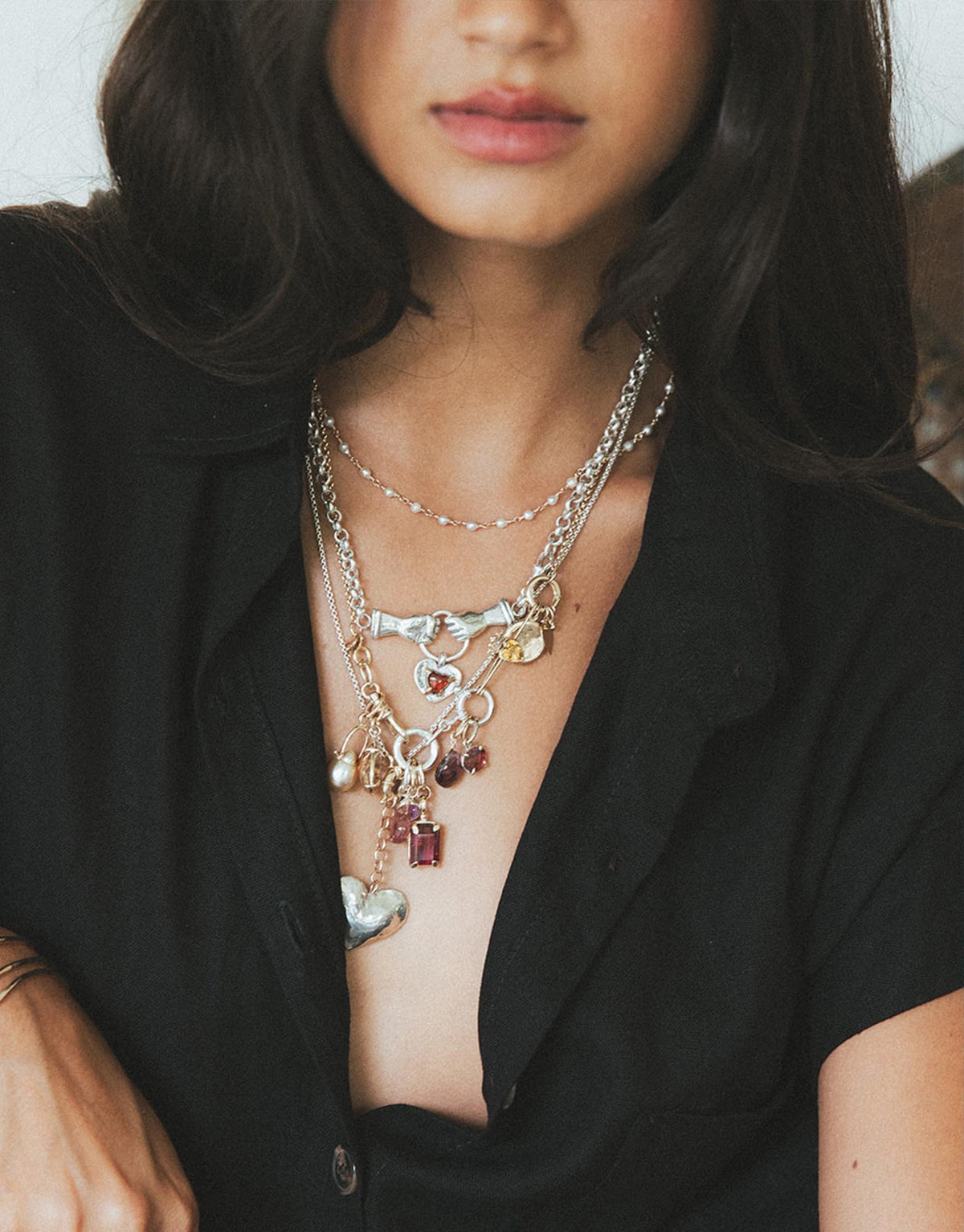 Model in a black blazer wearing layered charm necklaces
