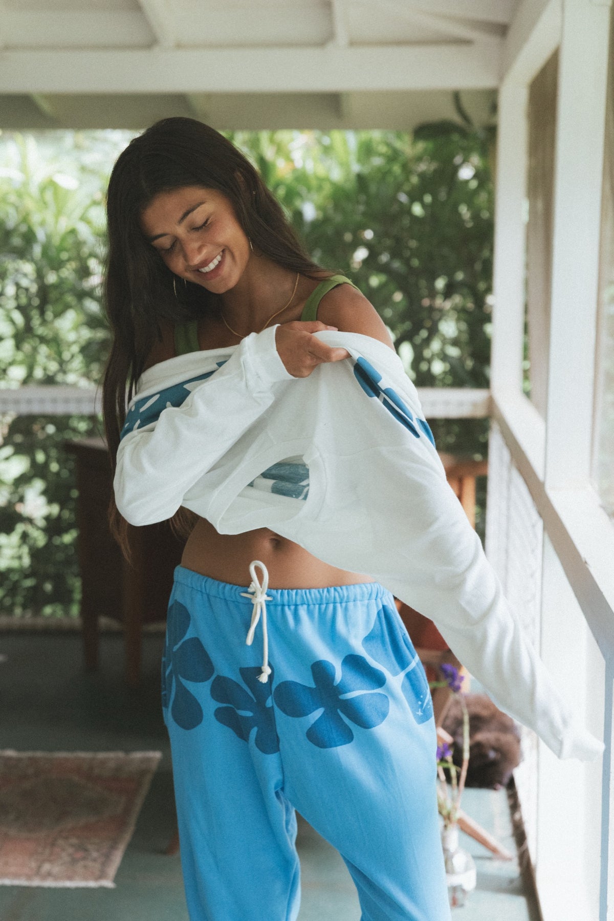 Model pulling on a hibiscus top by the porch screen