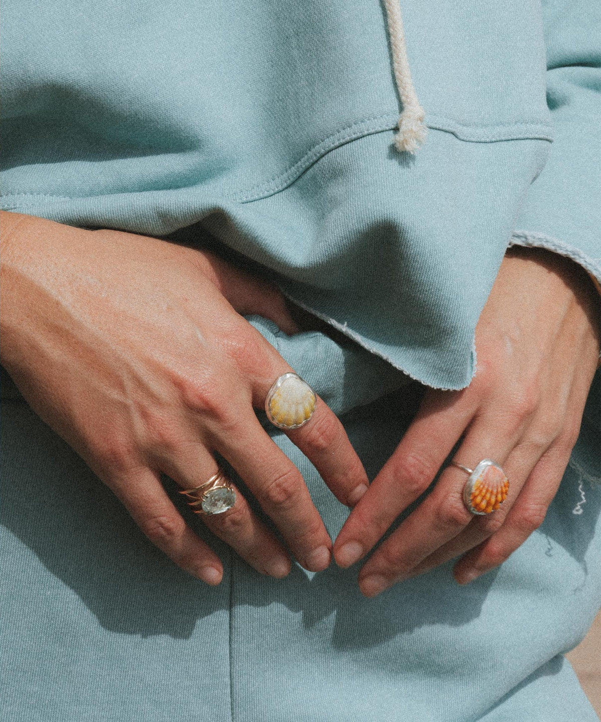 Hands with rings on a mint hoodie