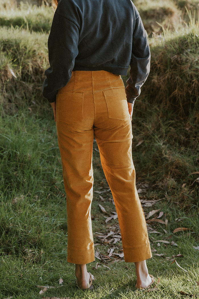 Model wearing Wings Hawaii retro pocket pants in marigold corduroy - back