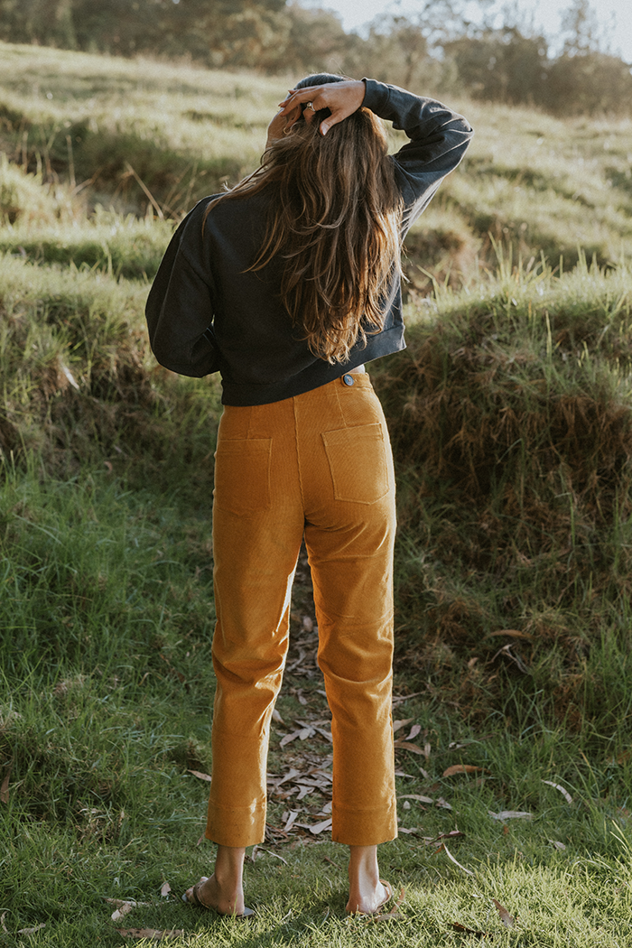 Model wearing Wings Hawaii retro pocket pants in marigold corduroy - back