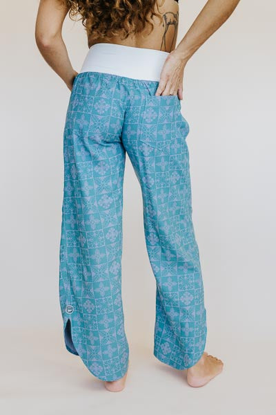 Model wearing Wings Hawaii pau hana pants in quilted ulu and plumeria print in surf blue - back view