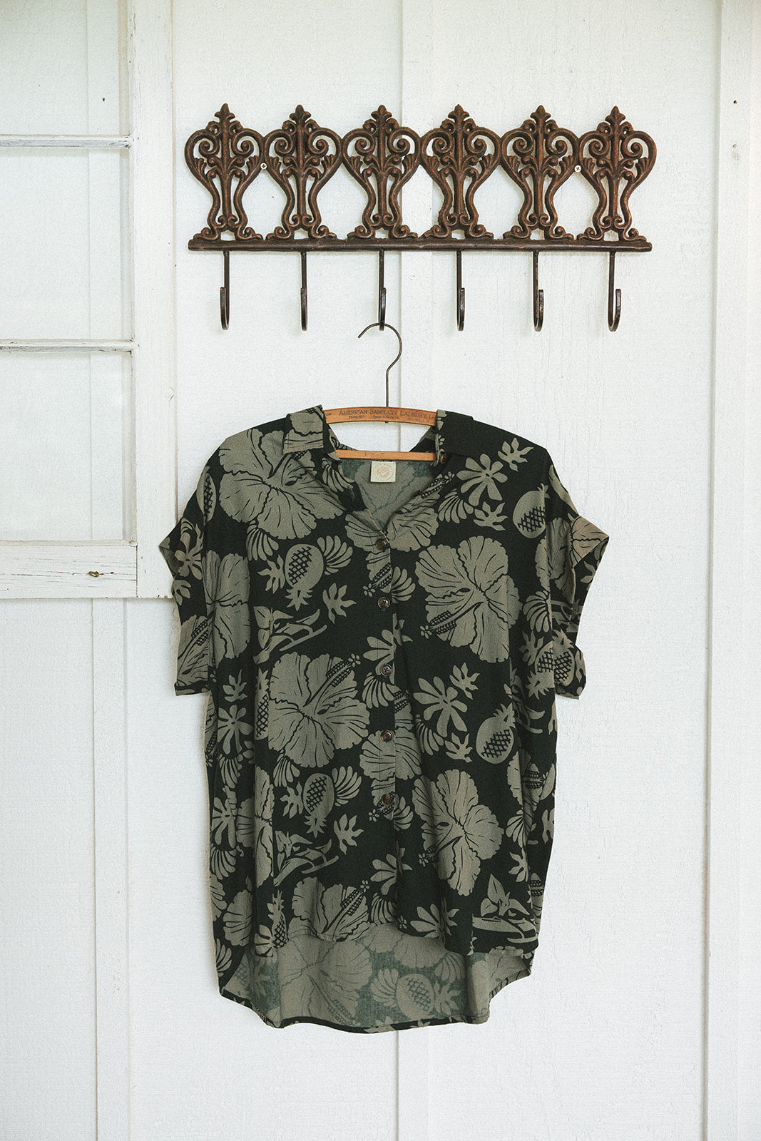 Wings Hawaii Short Sleeve Pocket Blouse in green Hana Forest aloha print. Designed in Maui, sewn in Bali. Modern women's aloha shirt. Small batch, sustainable apparel for beachy boho surfer style. Light and dark green print with hibiscus flowers, pineapples and Hawaiian outrigger canoes. 