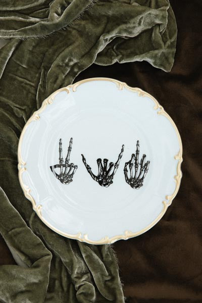 wings hawaii mixed signals vintage plate with gold rim, featuring skeleton hands in peace, shaka, and middle finger poses