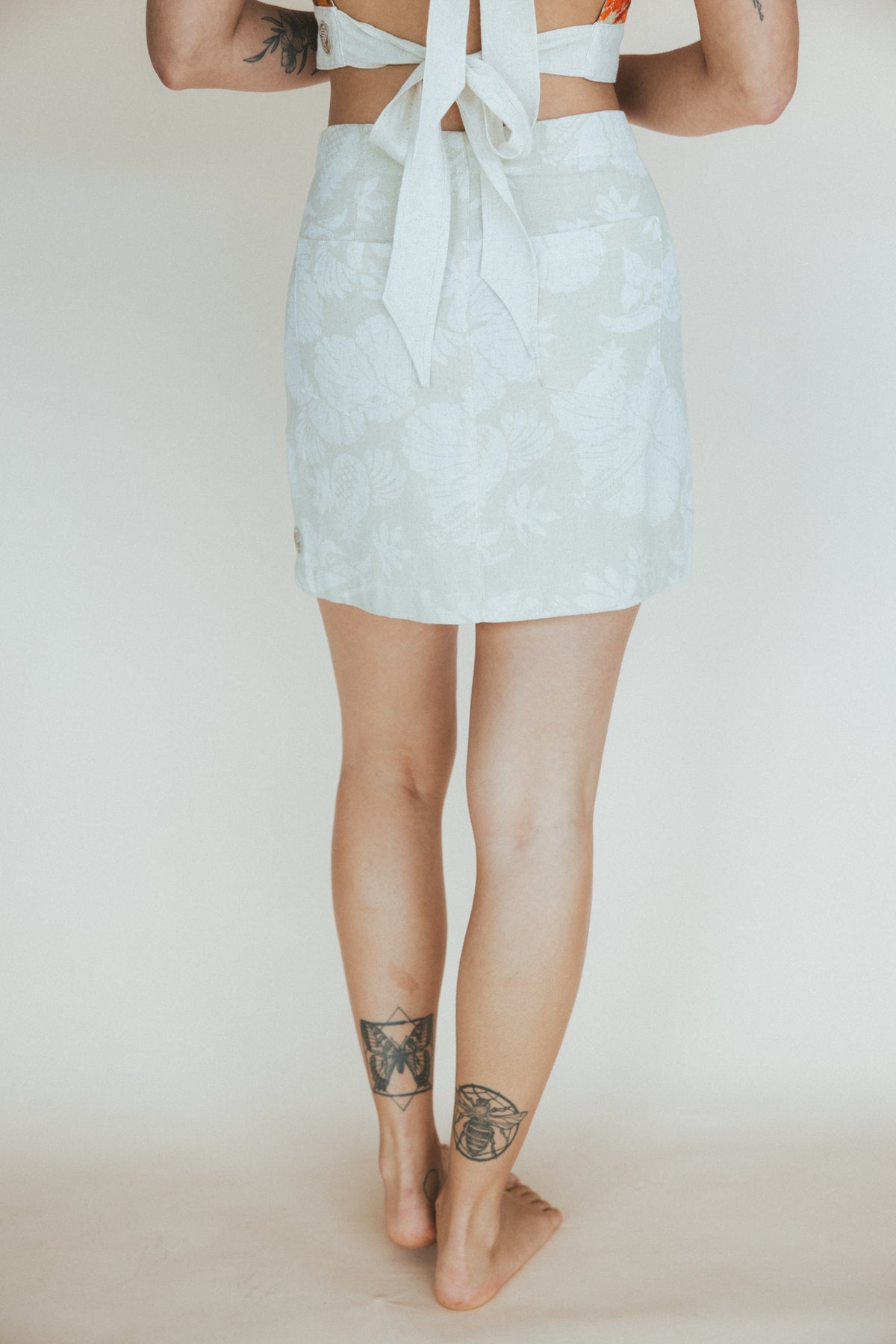Wings Hawaii Retro Pocket Mini Skirt in Hana Pearl. Neutral white and cream aloha print. Hand-drawn artwork designed in Maui, sewn in Bali. Small batch, sustainable, high quality women's apparel made with aloha. 
