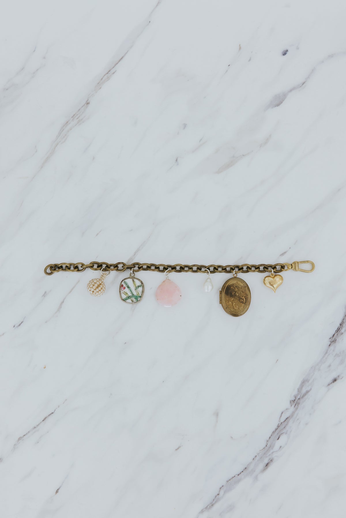 Wings Hawaii Vintage Charm Bracelet. Brass chain with mix of vintage charms, pink opal, pearls, and a locket. Fine jewelry handcrafted in Maui. 