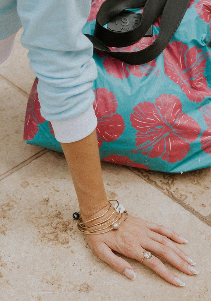 Hibiscus print tote by the pool, a wrist with bangles