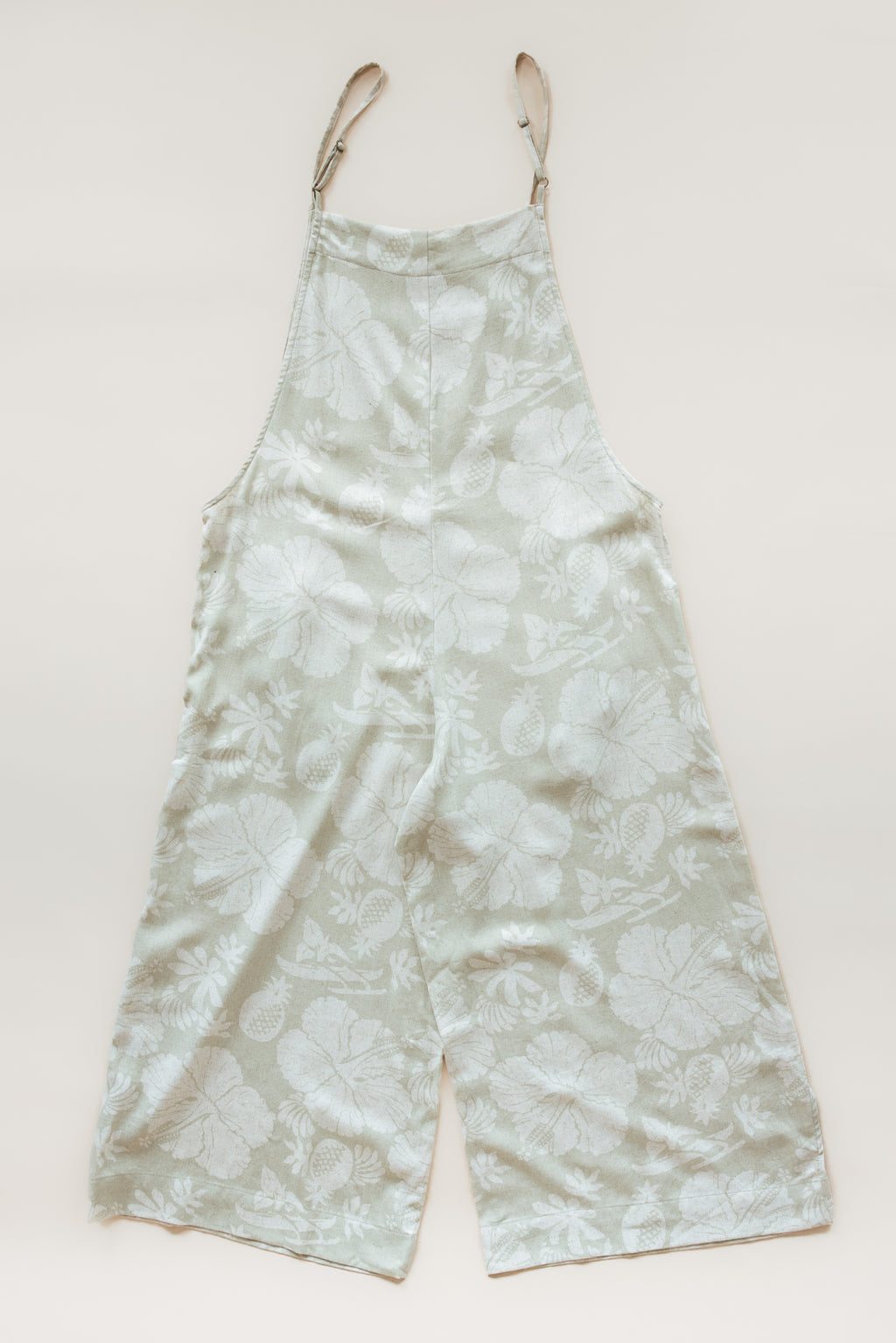 Wings Hawaii women's aloha print overalls in Hana Pearl. Designed in Maui, made in Bali. Cream white neutral tropical pattern with hibiscus florals, pineapples, and Hawaiian outrigger canoes. Adjustable straps, wide leg, relaxed fit, front and side pockets. Small batch, sustainable clothing for beachy, boho style. 