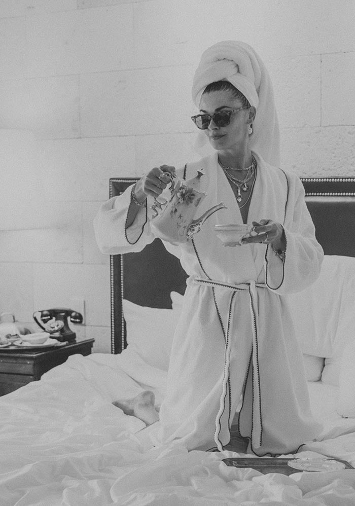 Model in a robe and towel on the bed, in black and white
