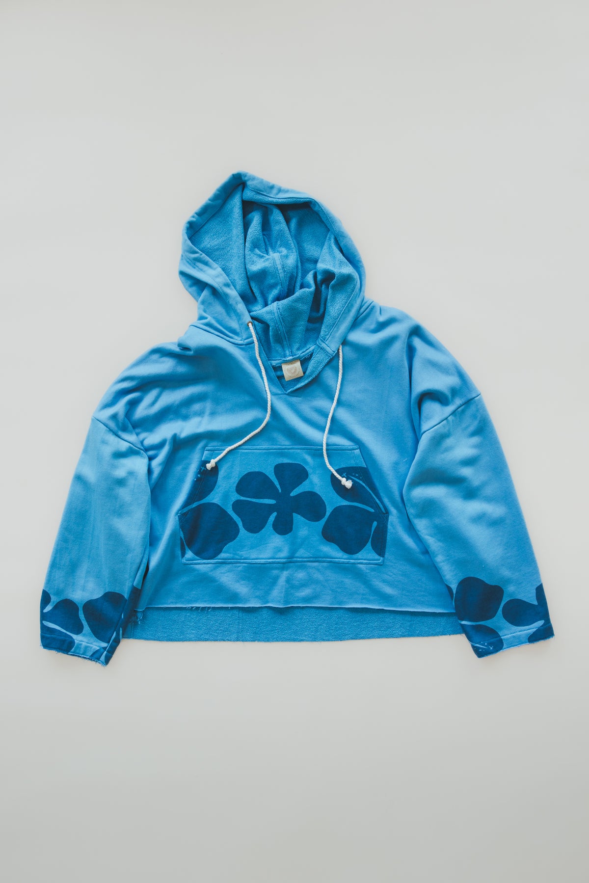 Wings Hawaii crop beach hoodie in blue crush hibiscus print. Designed in Maui, sewn in Bali. Cozy french cotton terry, drawstring hood, front kangaroo pouch, wide sleeves. Coastal chic surfer girl vibes. 