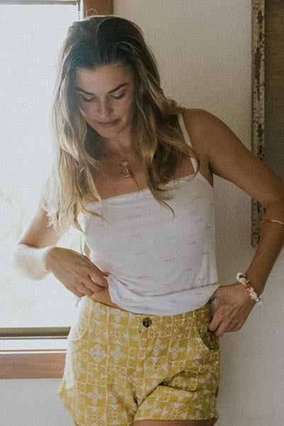 Model wearing Wings Hawaii retro pocket shorts in quilted ulu and plumeria print in marigold