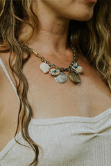 Model wearing Wings Hawaii brass chain charm necklace with sand dollar and shell charms and locket thumbnail