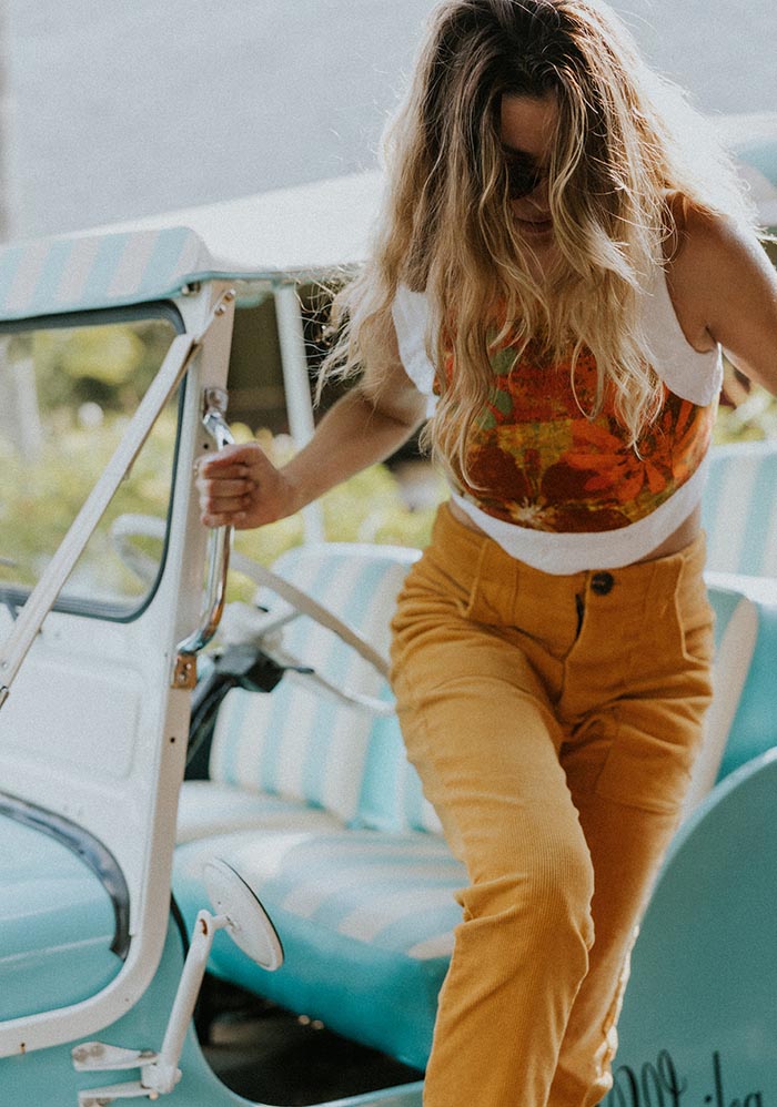 Model stepping out of the vintage car in orange pants