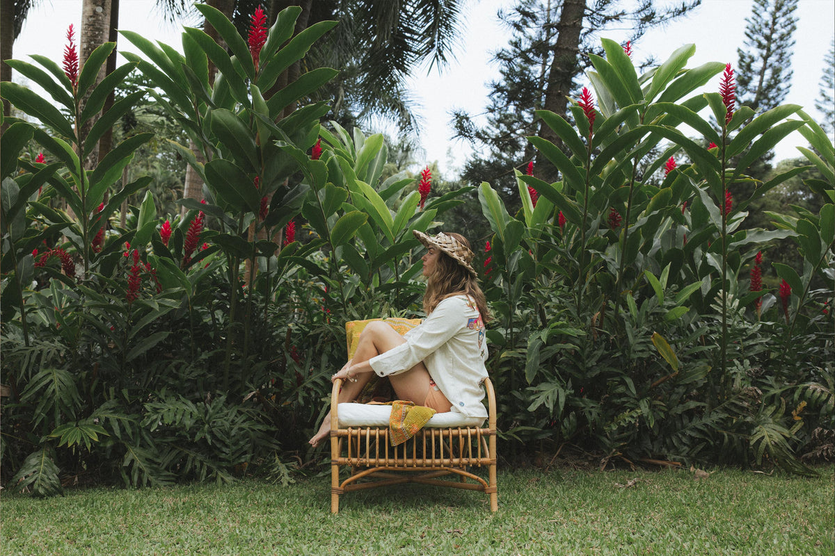 Model on a rattan chair in a tropical garden
