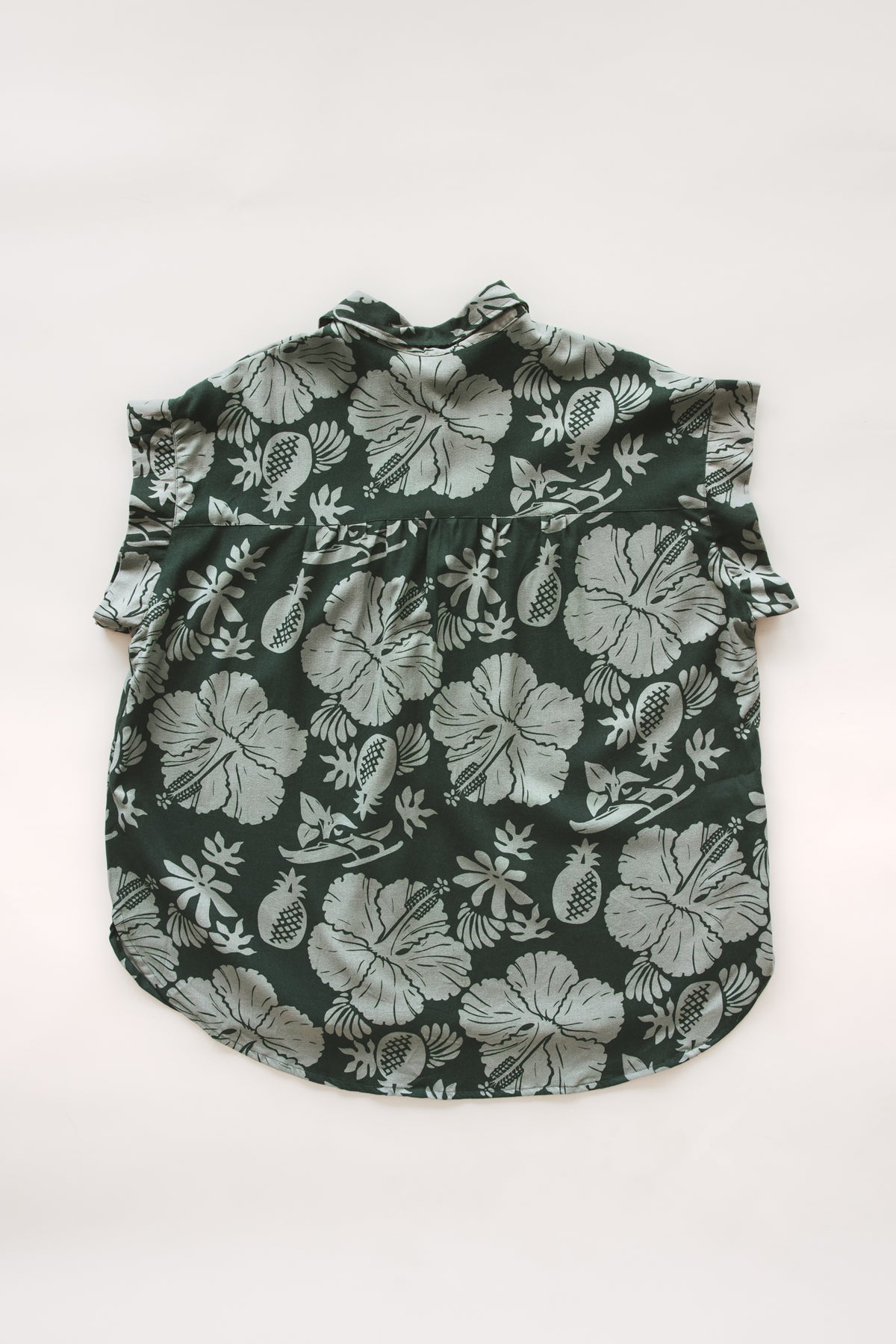 Wings Hawaii Short Sleeve Pocket Blouse in green Hana Forest aloha print with hibiscus flowers, pineapples and Hawaiian outrigger canoes. Modern women's aloha shirt. Original artwork designed in Maui, sewn in Bali. Small batch, sustainable apparel for beachy boho surfer style. 