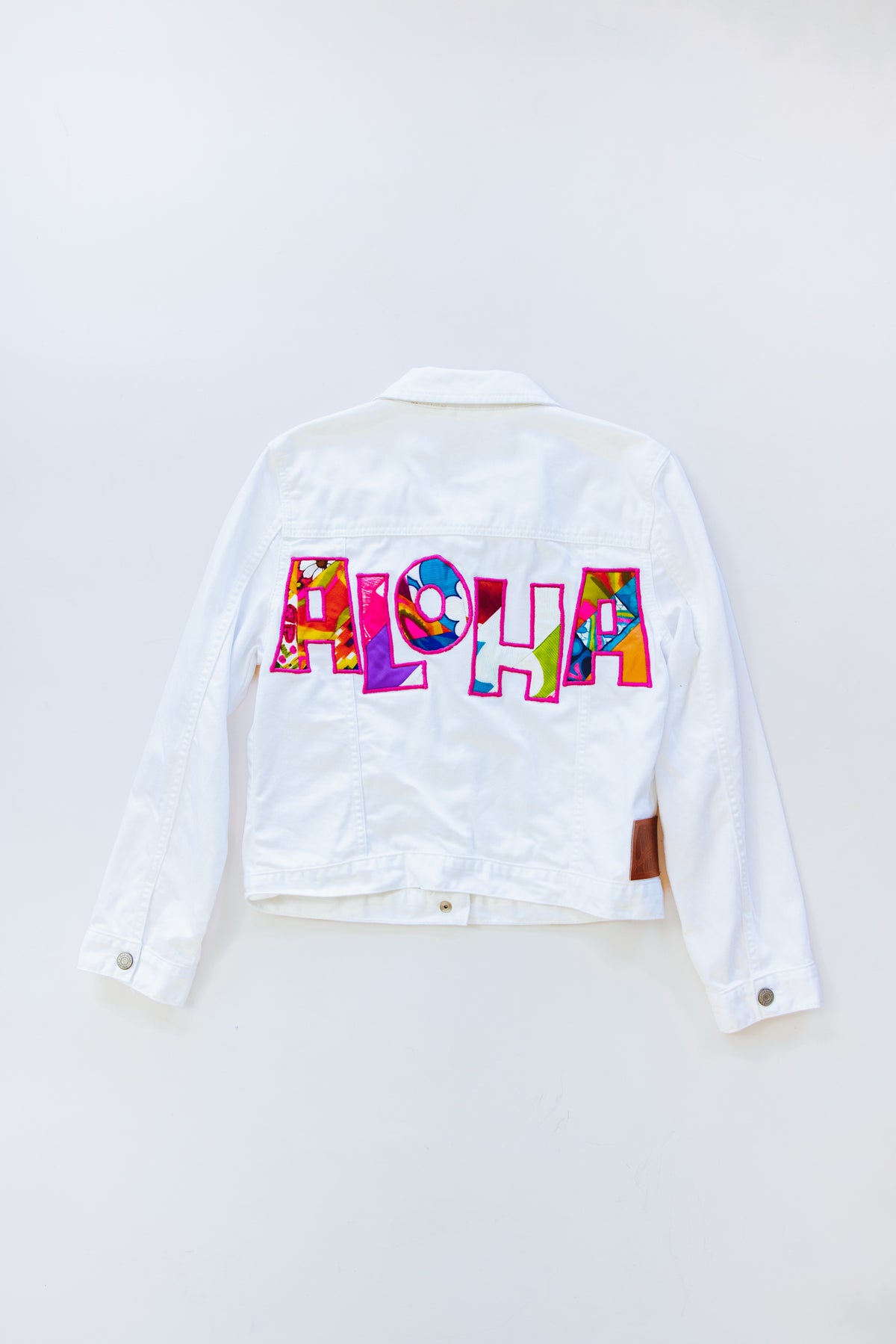 Wings Hawaii Aloha patch denim jacket. White jean jacket with ALOHA design in vintage aloha print fabrics. Upcycled, sustainable, small batch, creative fashion handmade in Maui. 