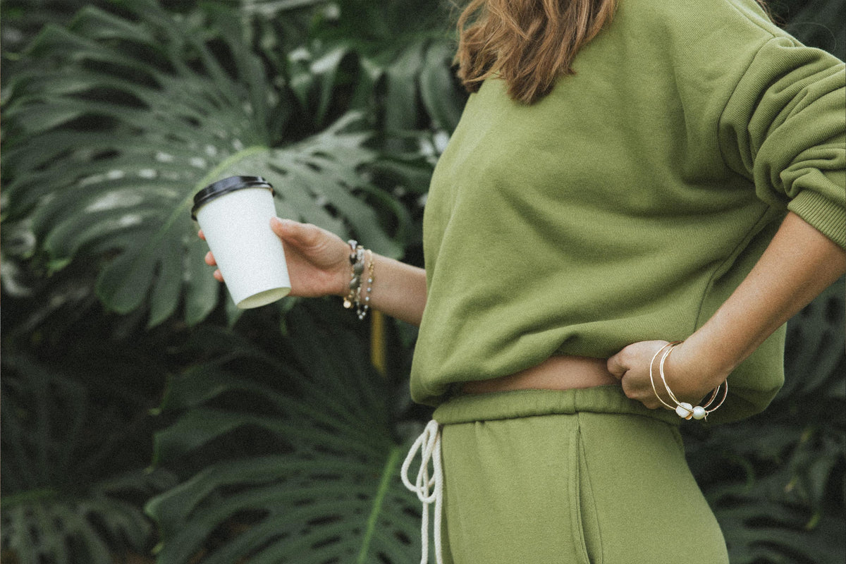 Model in a green sweat set holding a coffee cup
