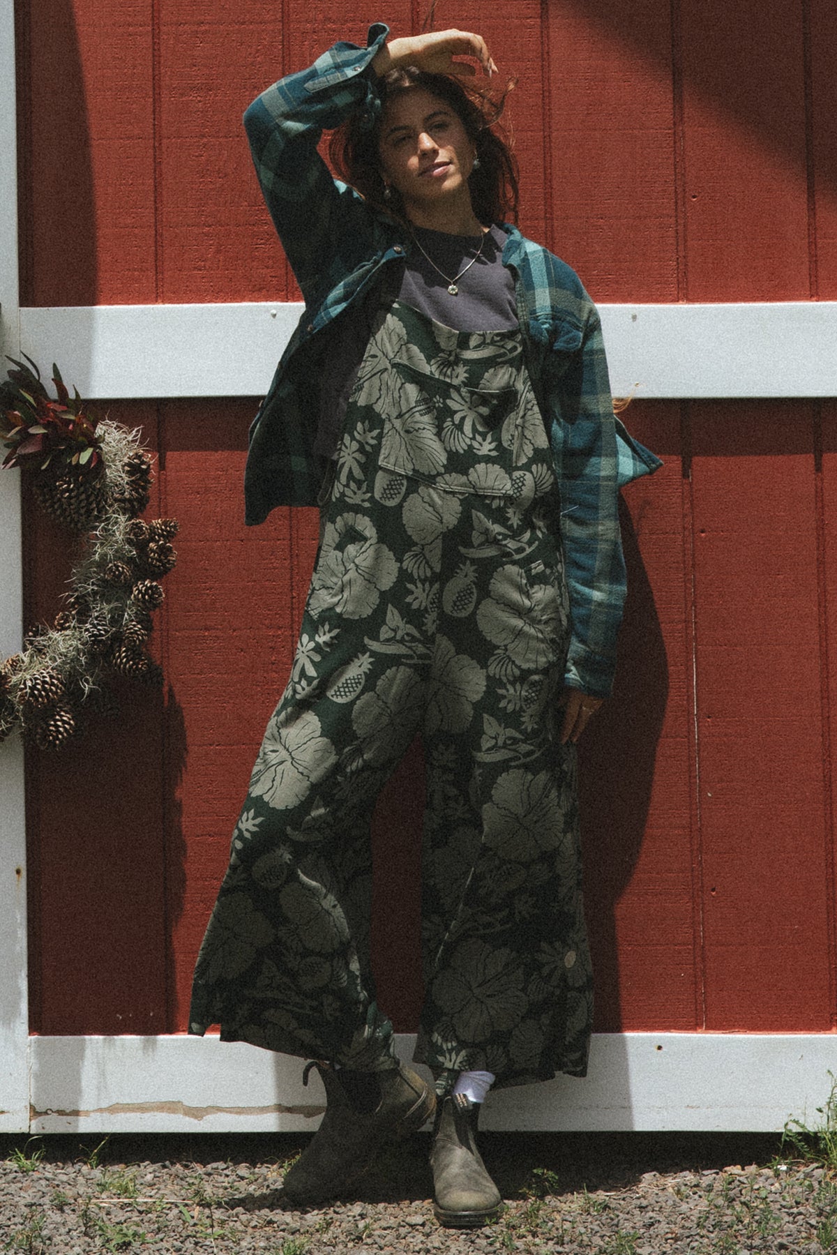 Wings Hawaii women's aloha print overalls in Hana Forest. Designed in Maui, made in Bali. Dark green tropical pattern with hibiscus florals, pineapples, and Hawaiian outrigger canoes. Adjustable straps, wide leg, relaxed fit, front and side pockets. Small batch, sustainable clothing for beachy, boho style. 