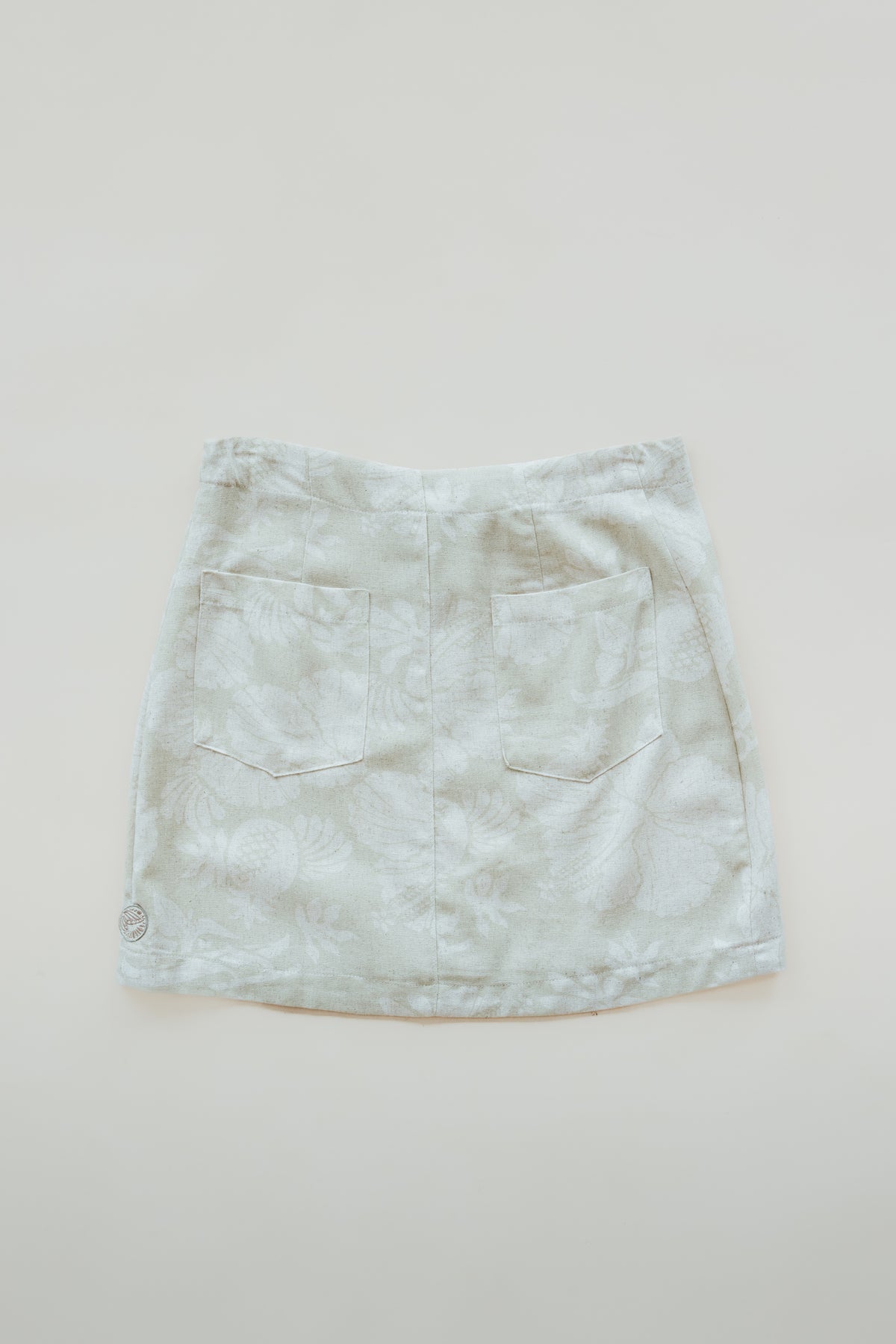 Wings Hawaii Retro Pocket Mini Skirt in Hana Pearl. Neutral white and cream aloha print. Hand-drawn artwork designed in Maui, sewn in Bali. Small batch, sustainable, high quality women's apparel made with aloha. 