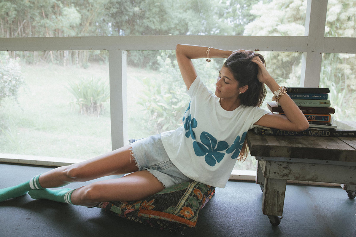Model in a hibiscus tee lying on a porch
