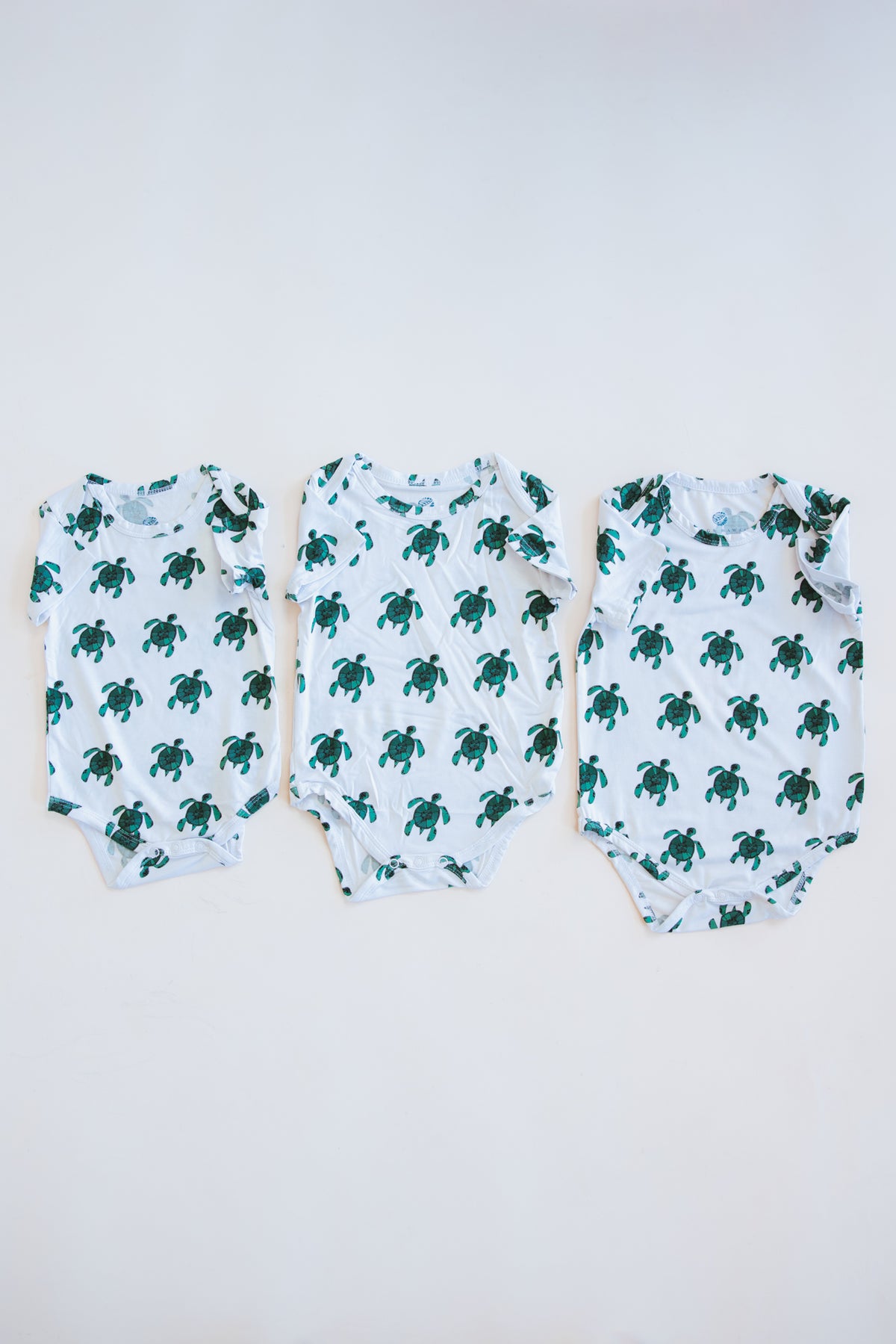 Wings Hawaii Honu baby onesie with Hawaiian sea turtles. Original artwork designed in Maui. Island-inspired keiki apparel and gifts. Best baby shower gifts with aloha from Hawaii. 