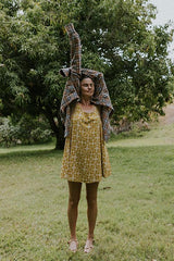 Wings Hawaii model wearing trapeze mini dress in ulu and plumeria print in marigold thumbnail