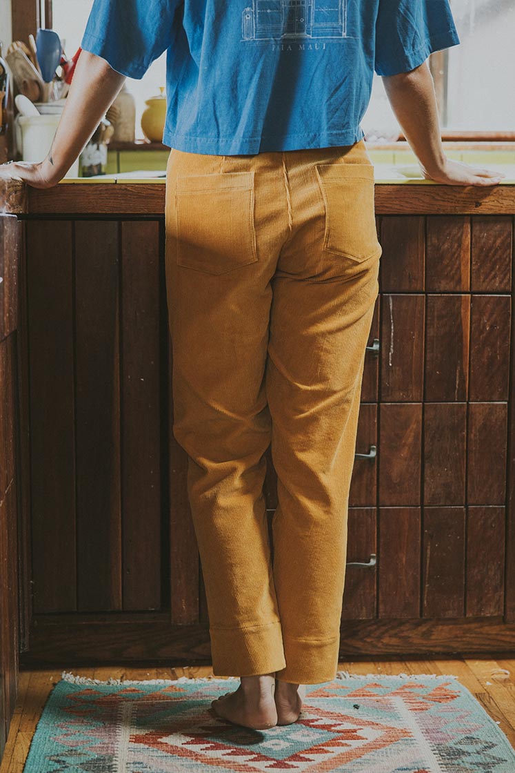 Model wearing Wings Hawaii retro pocket pants in marigold corduroy - back