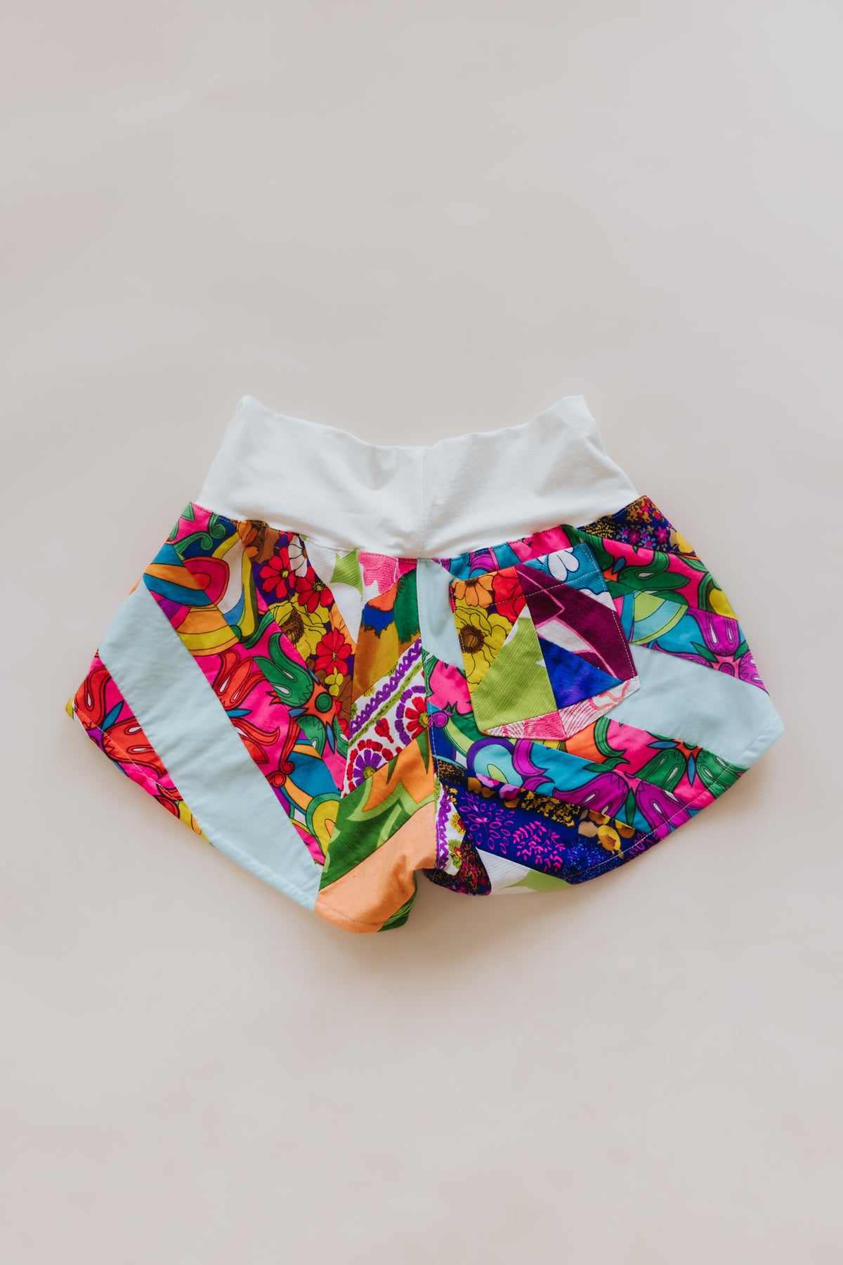 Wings Hawaii Patchwork Pau Hana Shorts in Tropic Rush. Handmade, one of a kind, upcycled vintage quilt fabric. Stretchy cotton waistband and back pocket. Made with aloha in Maui. Sustainable, small batch, slow fashion. 