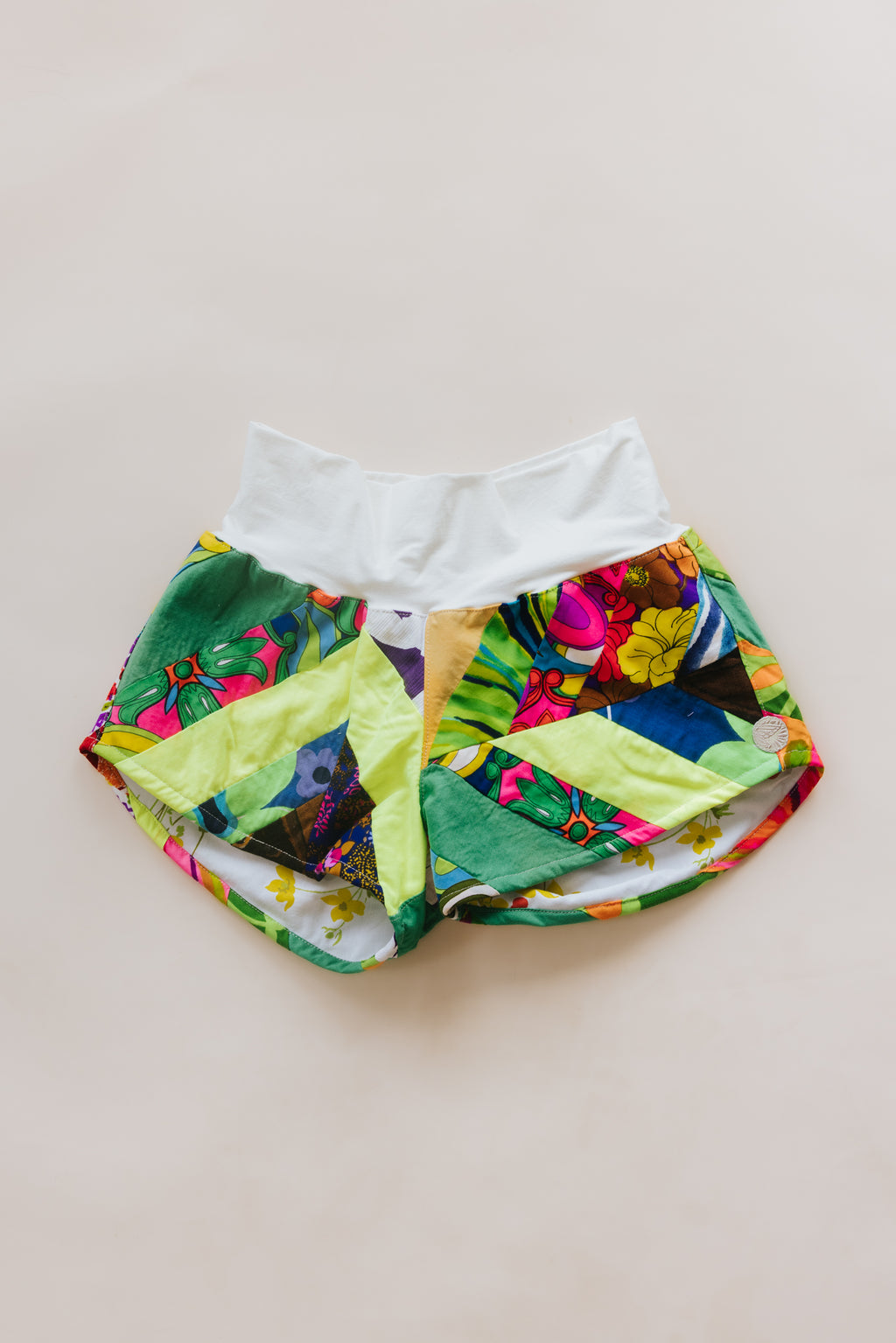 Wings Hawaii Patchwork Pau Hana Shorts in Tropic Rush. Handmade, one of a kind, upcycled vintage quilt fabric. Stretchy cotton waistband and back pocket. Made with aloha in Maui. Sustainable, small batch, slow fashion. 