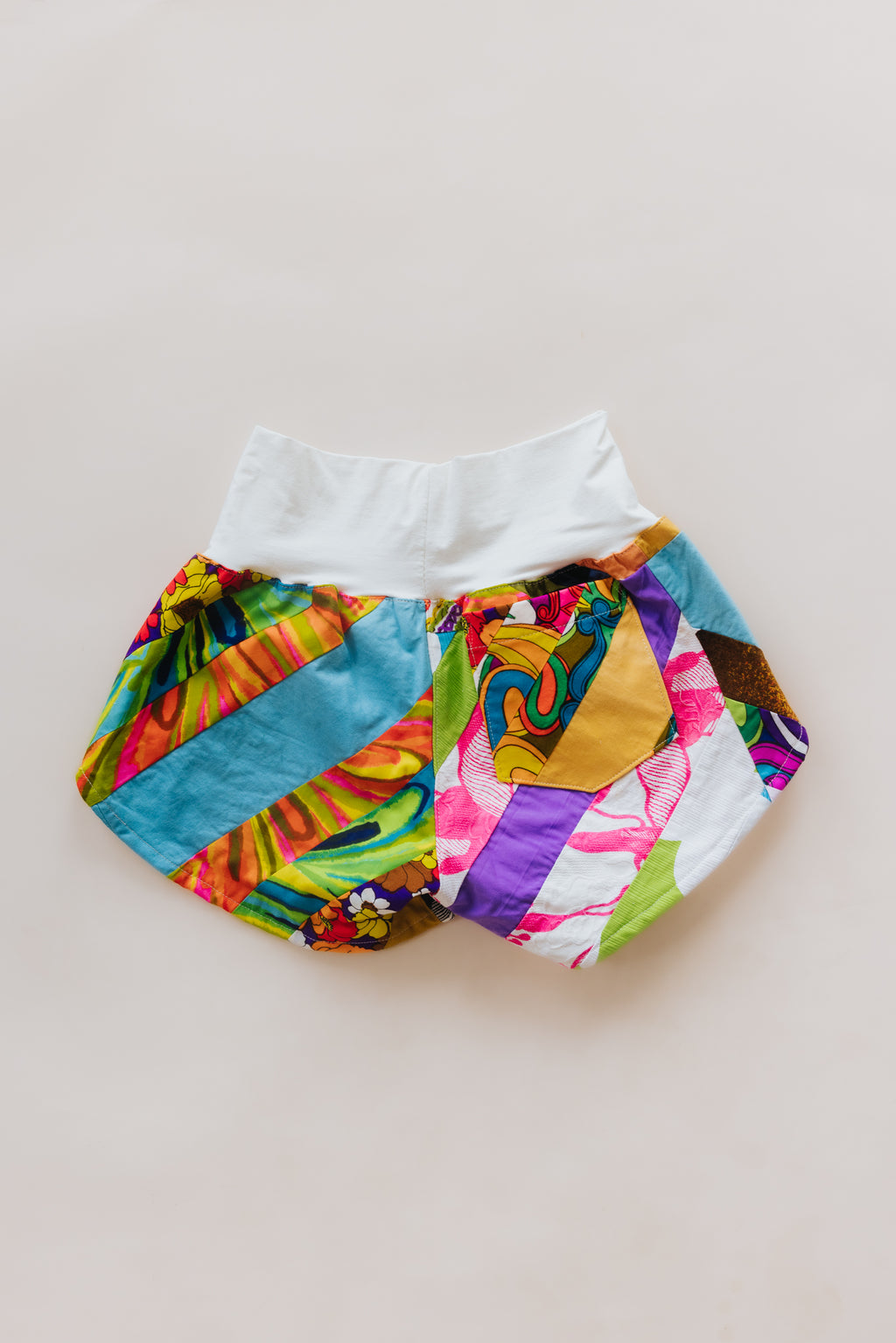 Wings Hawaii Patchwork Pau Hana Shorts in Tropic Rush. Handmade, one of a kind, upcycled vintage quilt fabric. Stretchy cotton waistband and back pocket. Made with aloha in Maui. Sustainable, small batch, slow fashion. 