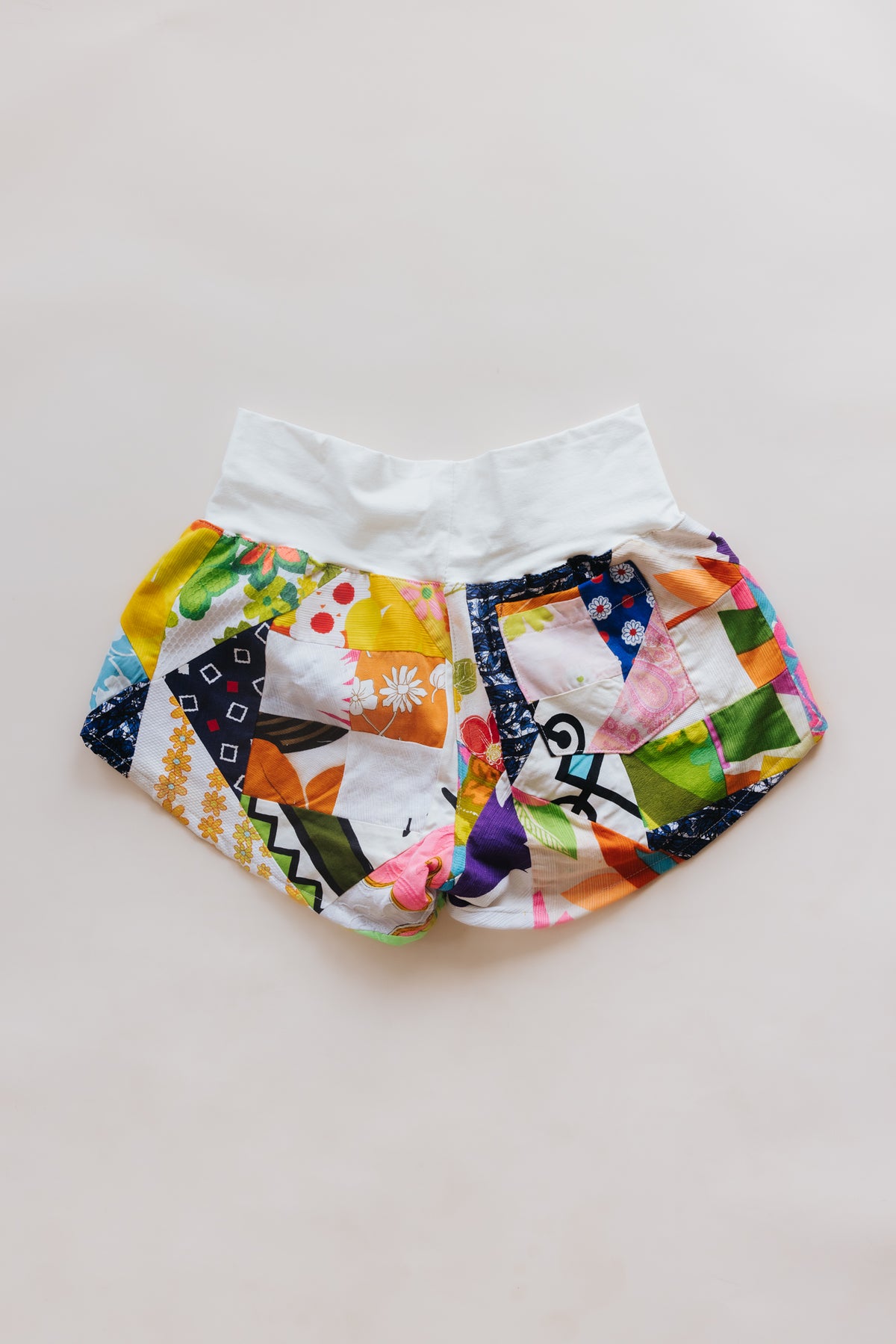 Wings Hawaii Patchwork Pau Hana Shorts in Daisy Lane. Handmade, one of a kind, upcycled vintage quilt fabric. Cozy cotton waistband and back pocket. Made with aloha in Maui. Sustainable, small batch, slow fashion. 