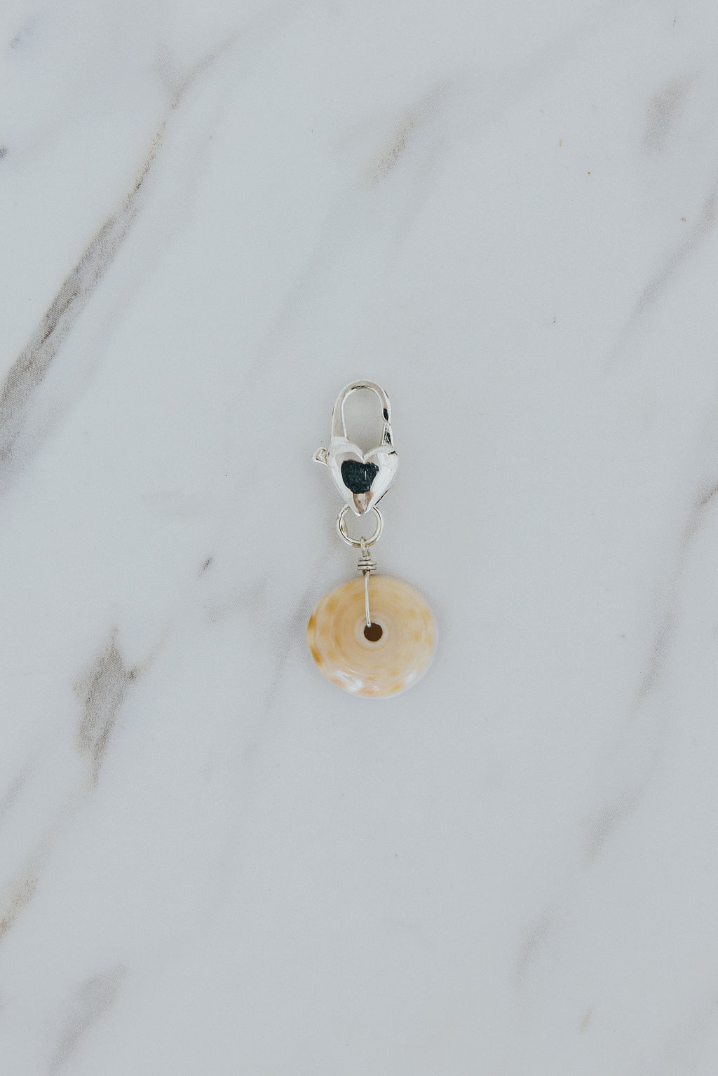 Wings Hawaii Puka shell with heart-shaped clasp in sterling silver. Boho beachy jewelry handmade in Maui. Clasp-on charm for modern charm necklaces made in Hawaii