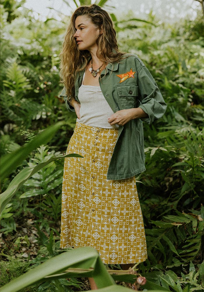 Model in a yellow print skirt and green jacket