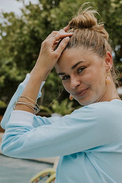 Model wearing charm hoop earrings adorned with Hawaiian sunrise shells in gold