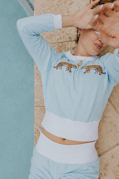 Model wearing Wings Hawaii Tiger raglan sweatshirt and blue french terry pau hana shorts. 