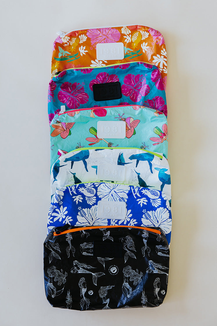 A collection of foldable adventure pouches in various colors and patterns, laid out flat.