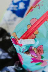 Closeup of Wings Hawaii foldable Tyvek adventure tote in kokio hibiscus print. Zipper detail says WINGS HI thumbnail