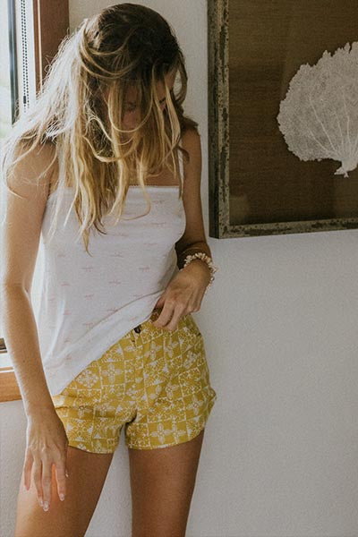 Model wearing Wings Hawaii retro pocket shorts in quilted ulu and plumeria print in marigold