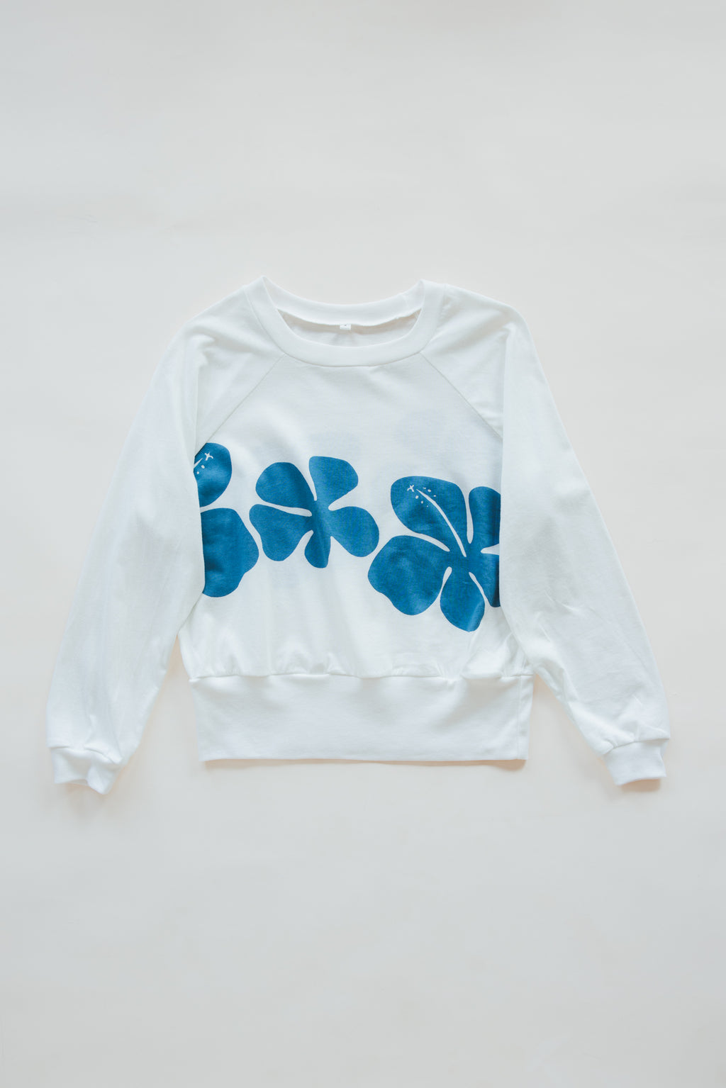 Wings Hawaii women's Hibiscus Raglan sweatshirt. White with blue vintage tropical floral print. Designed in Maui, made in Bali. Small batch, sustainable, eco-conscious clothing. 
