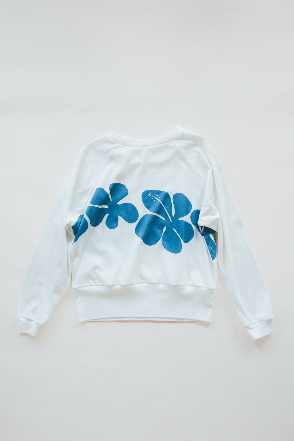 Wings Hawaii women's Hibiscus Raglan sweatshirt. White with blue vintage tropical floral print. Designed in Maui, made in Bali. Small batch, sustainable, eco-conscious clothing. 