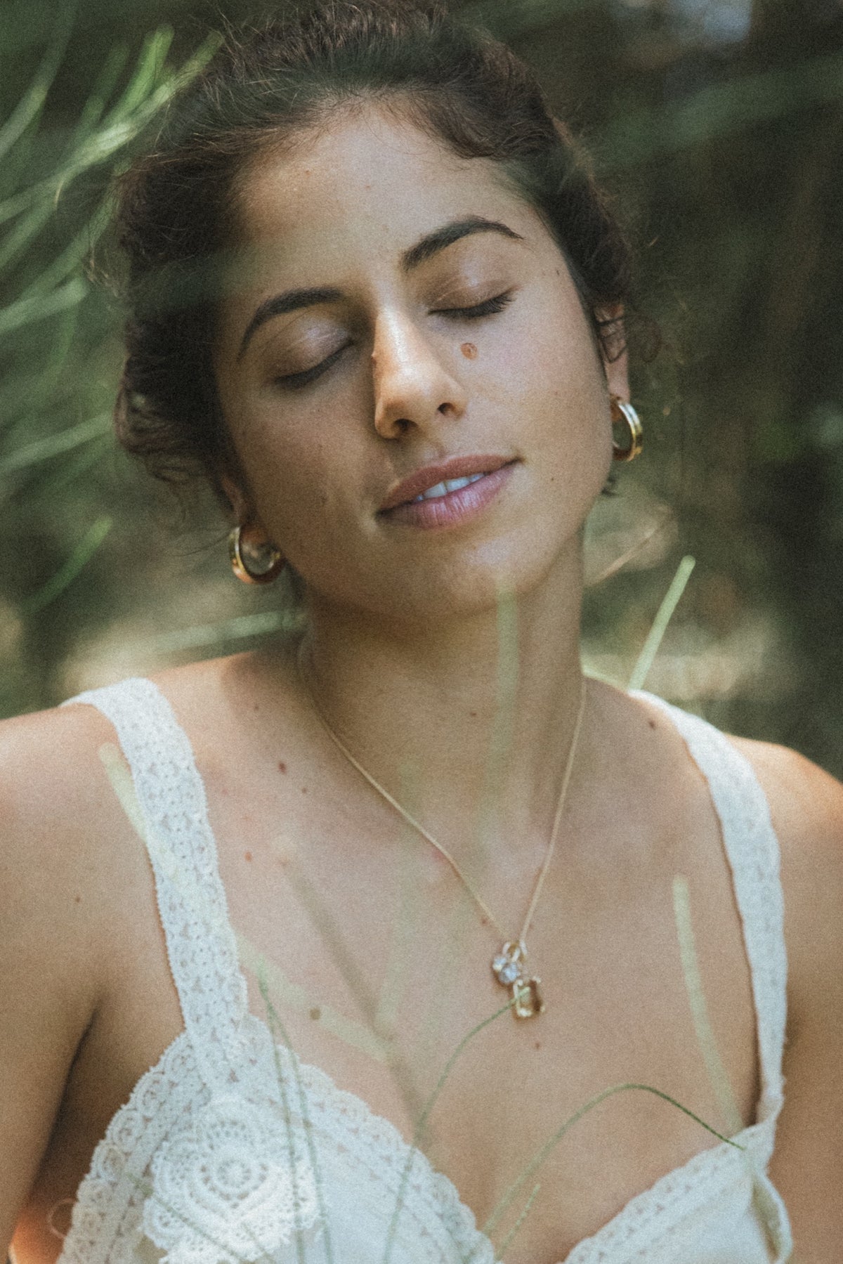 Model in a white dress in the forest wearing a Wings necklace