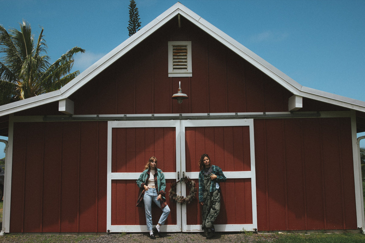 Two models in front of a red barn upcountry