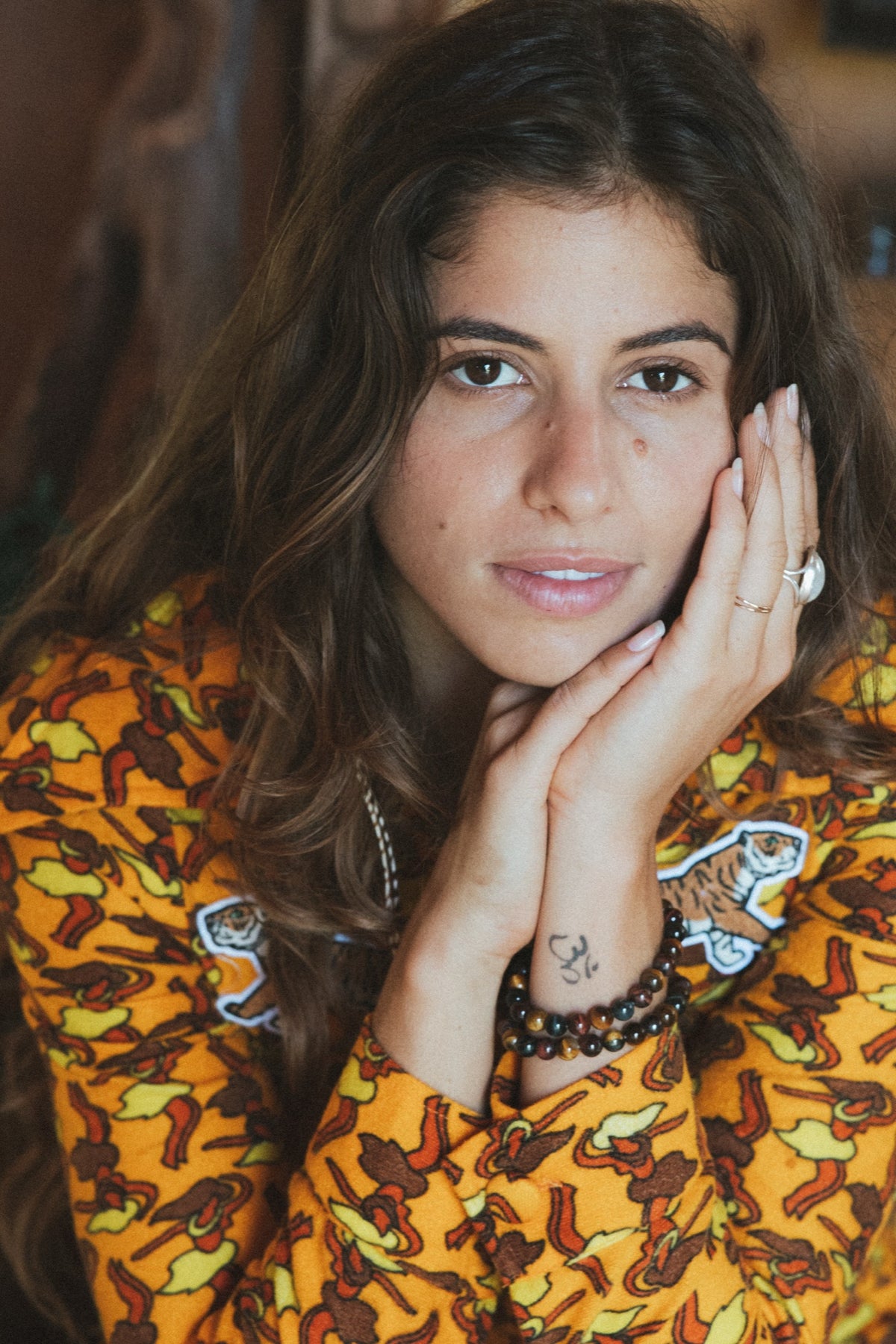 Model in a tiger print dress, hands at her face wearing rings