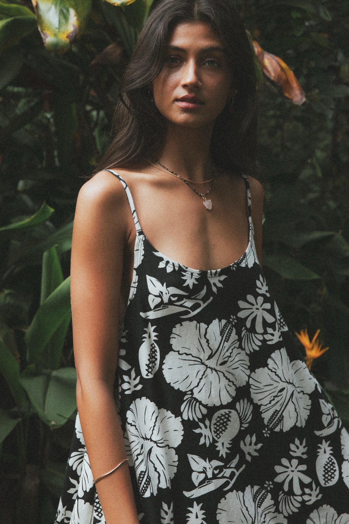 Model in a black and white floral dress among tropical leaves