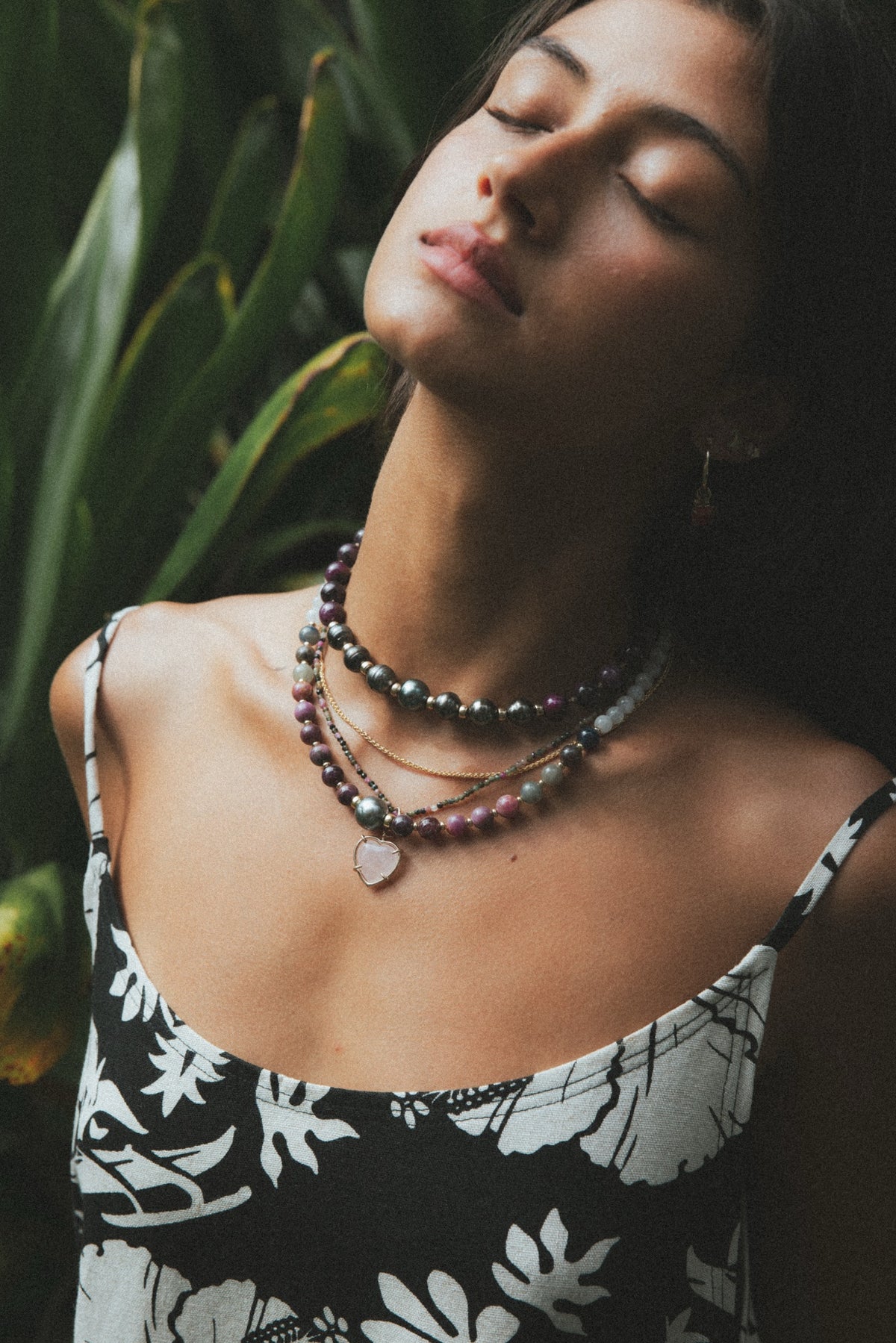 Model with eyes closed wearing layered Wings necklaces