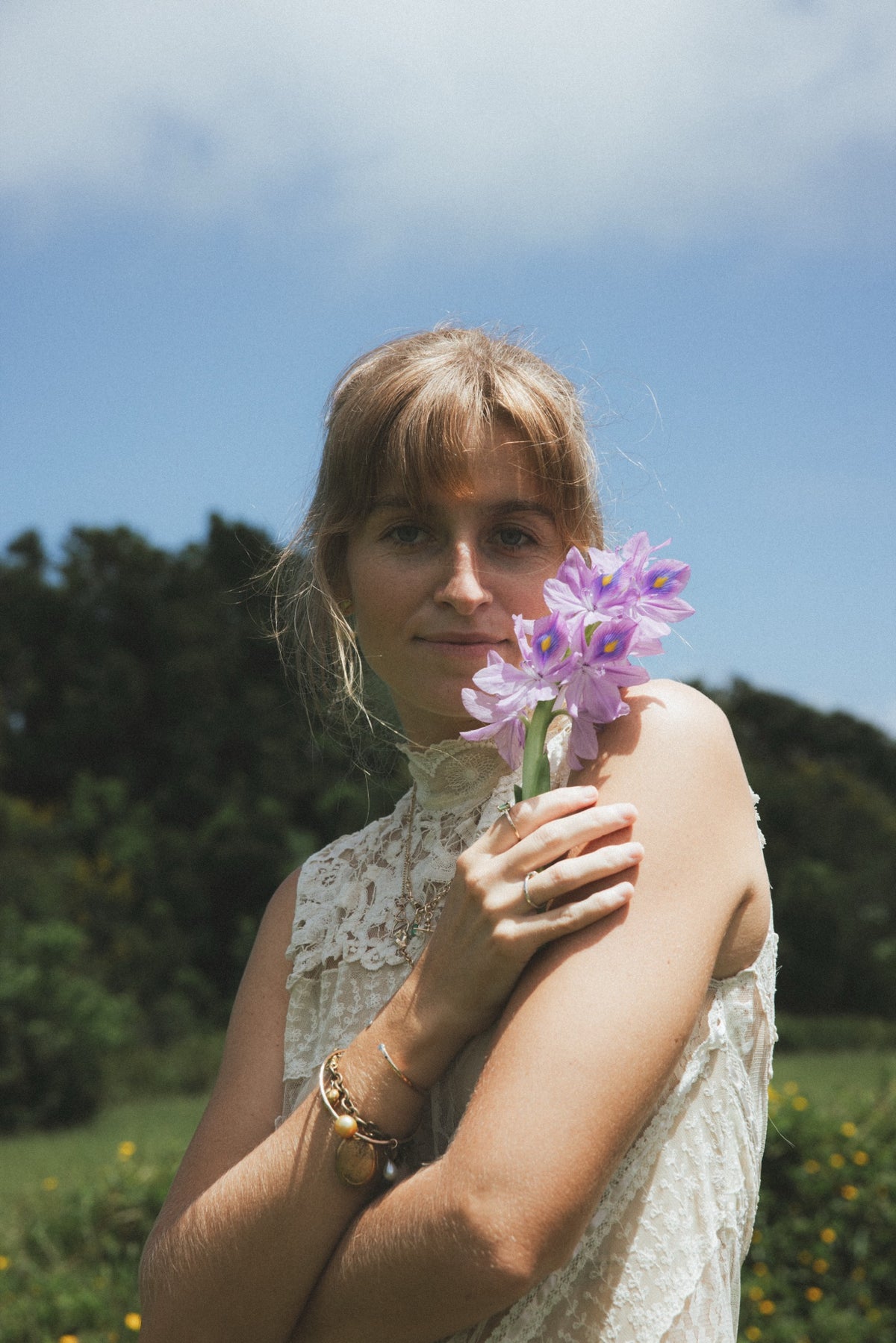 Model in a lace dress holding purple water hyacinths