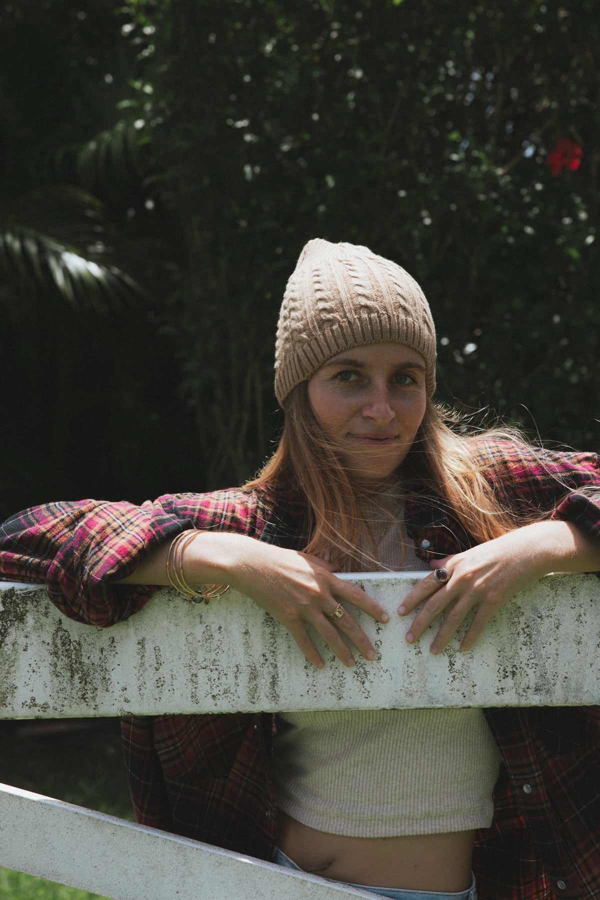 Model in a beanie leaning on a white fence