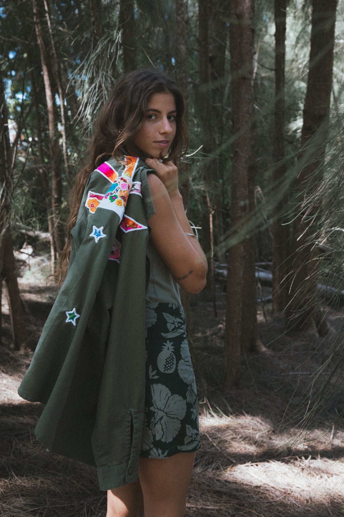 Back of an army jacket with a sun and moon patch in the forest