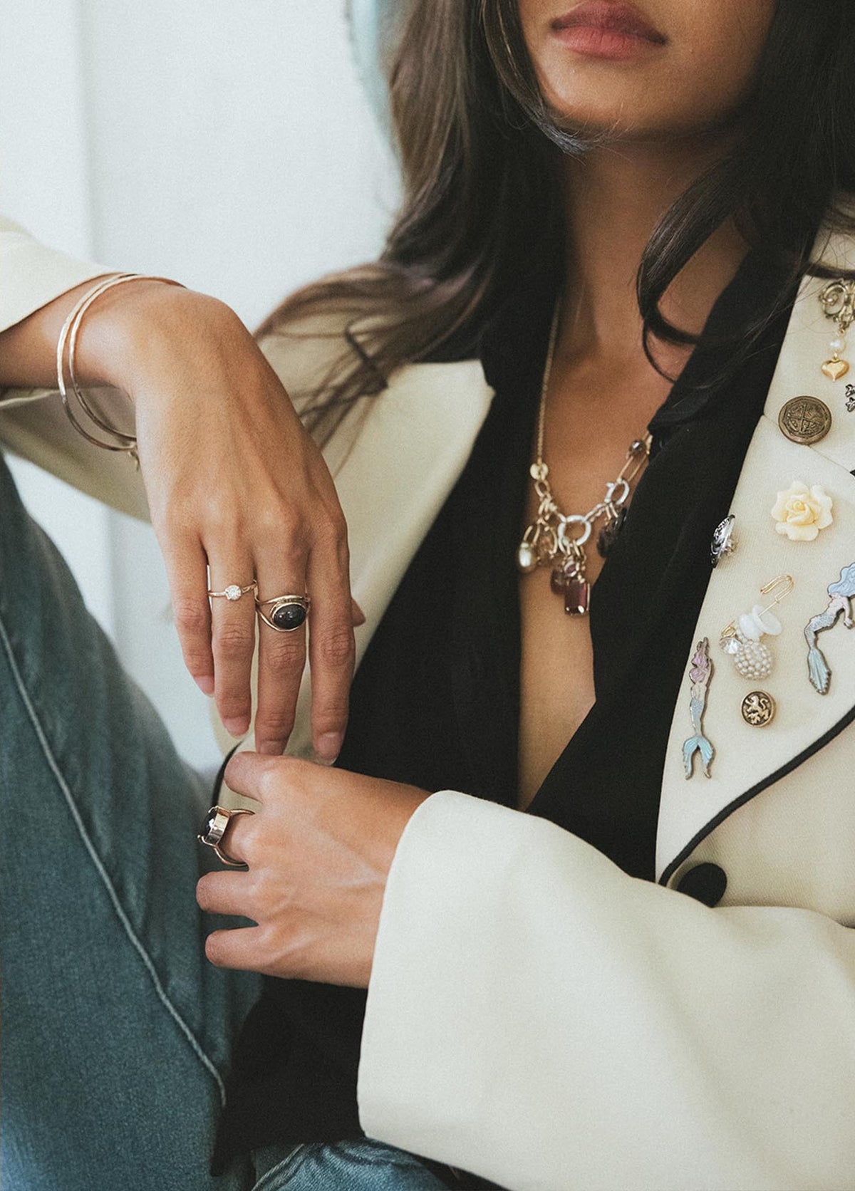 Hands with rings resting on a cream blazer